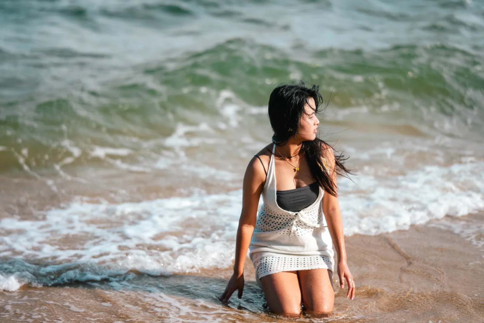 女生跪在浪花里，头发被风吹起，望向大海，东海岸公园海边写真