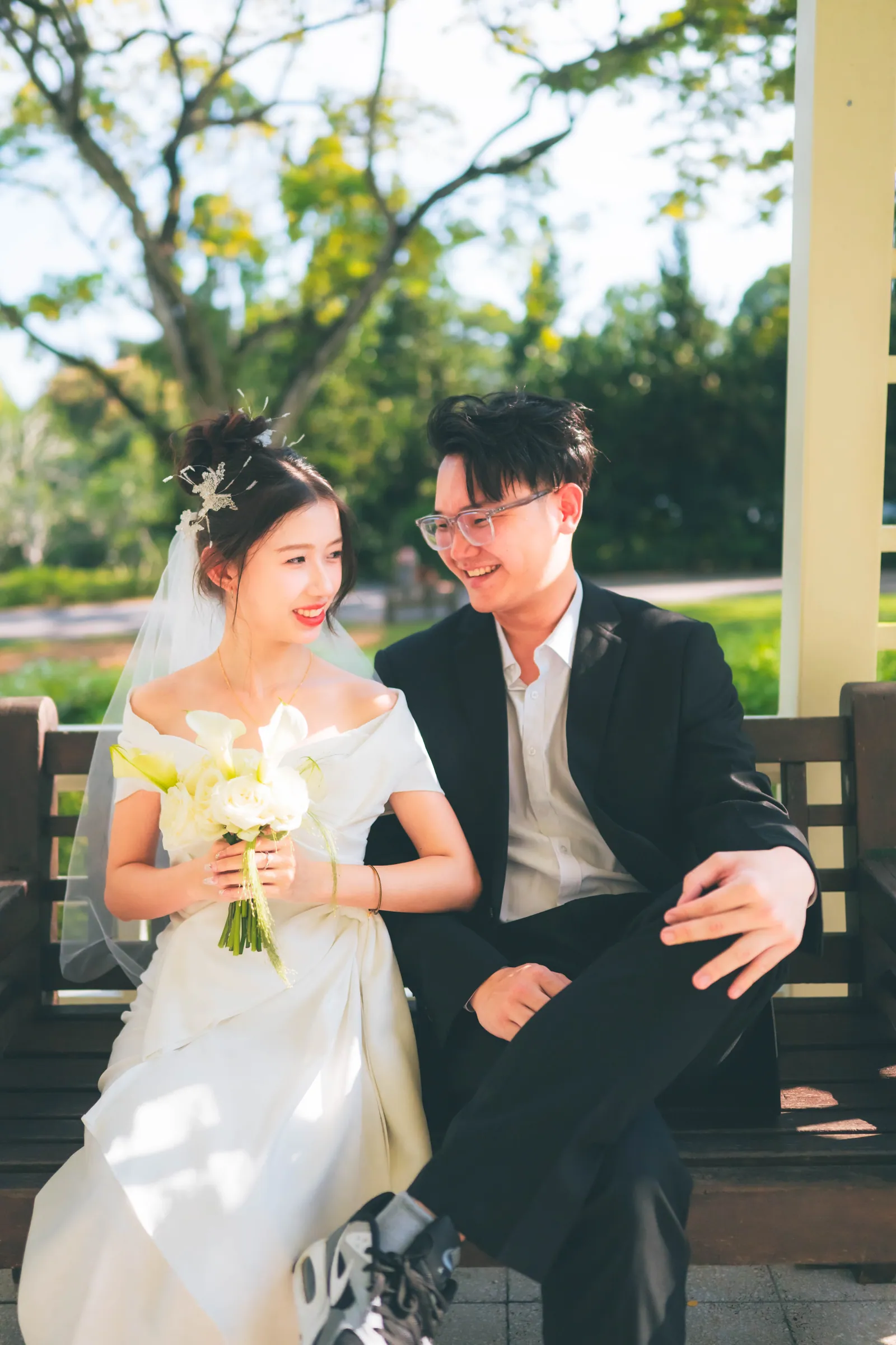Newlyweds laughing together on a wooden bench after their solemnisation, Singapore