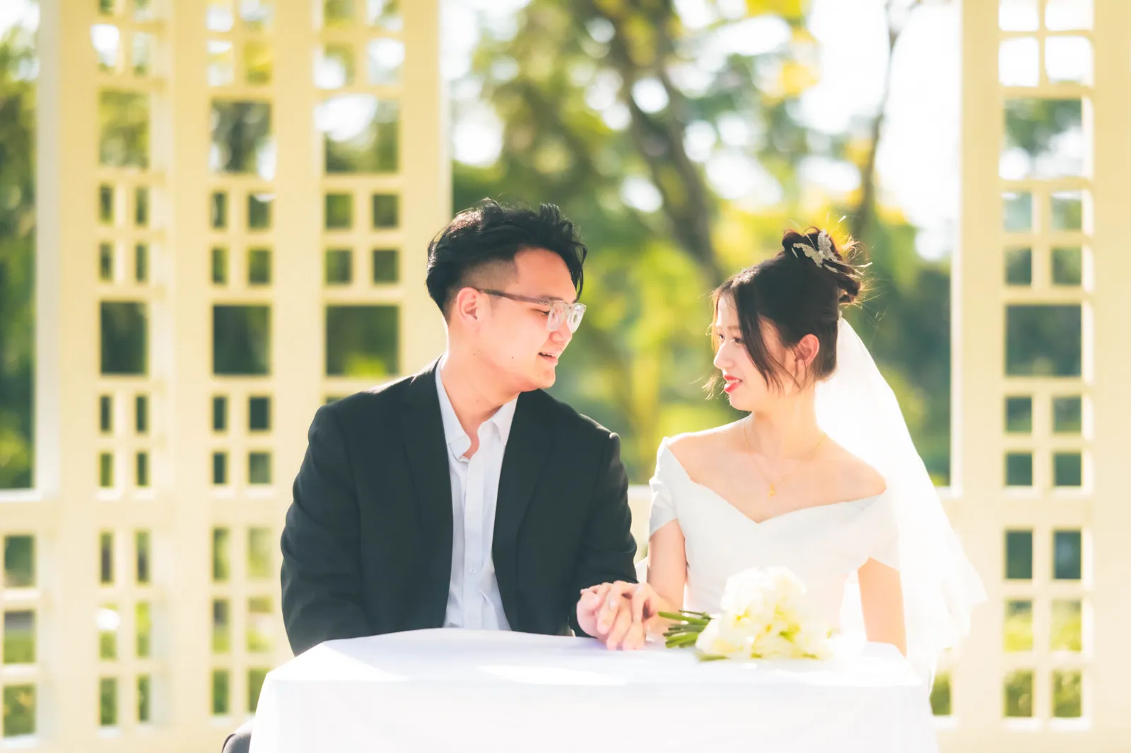 Couple holding hands at the solemnisation table under a white gazebo, Singapore ROM