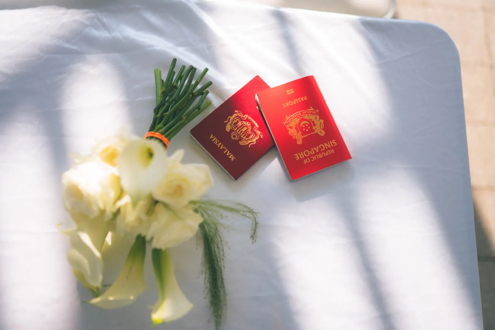 Malaysian and Singaporean passports next to a white bouquet on the solemnisation table
