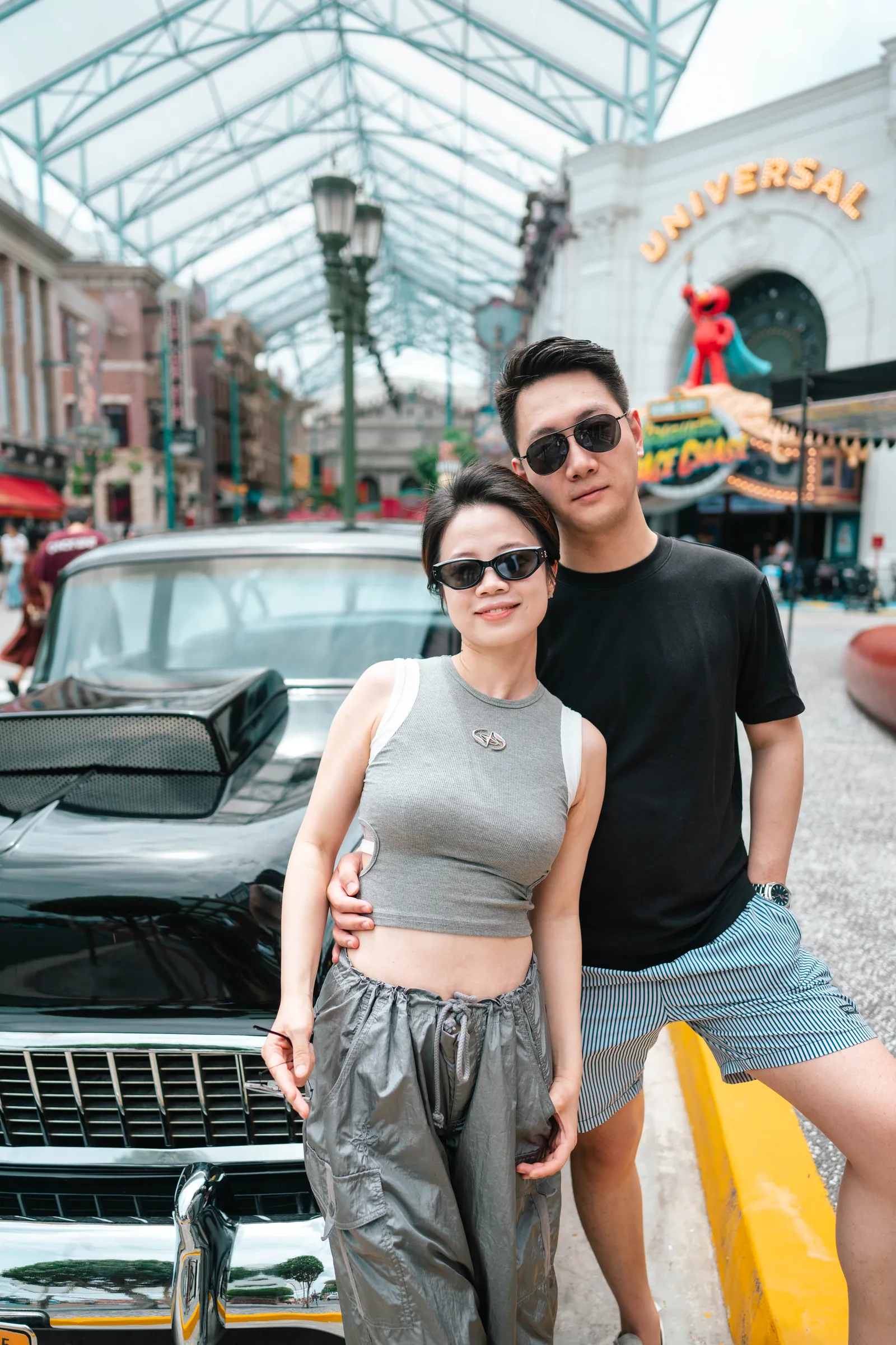 新加坡环球影城情侣旅拍:戴墨镜的情侣在好莱坞大道的老爷车旁合影